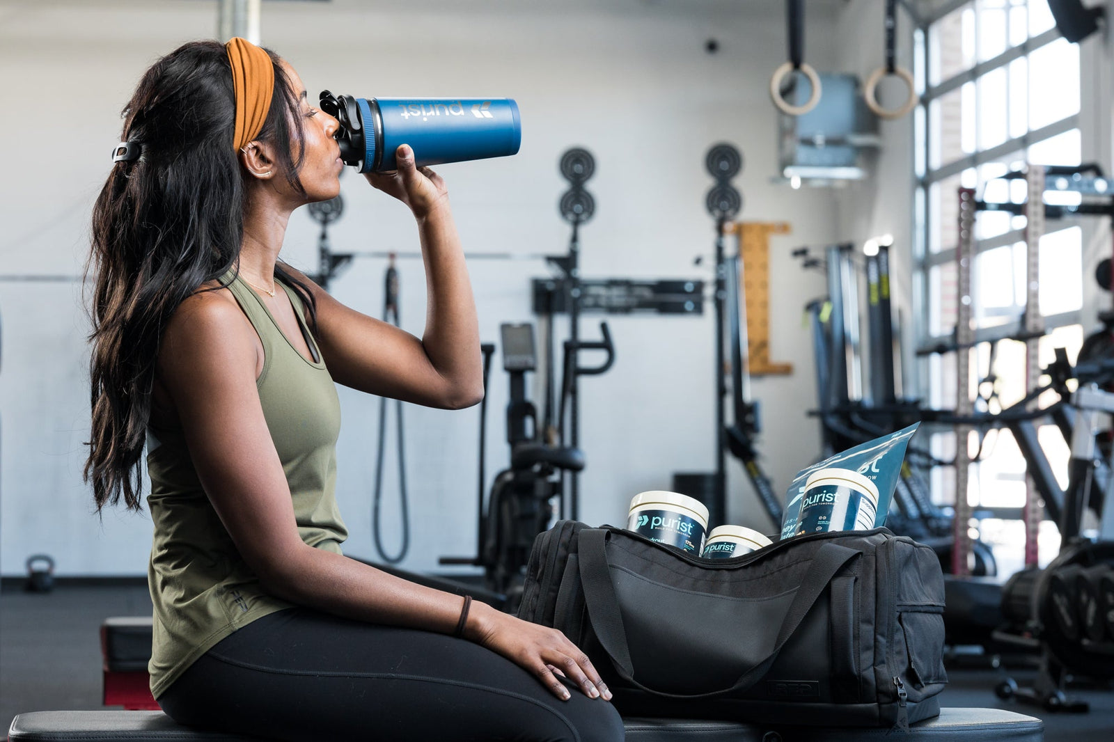 An athlete drinks from a shaker bottle in the gym