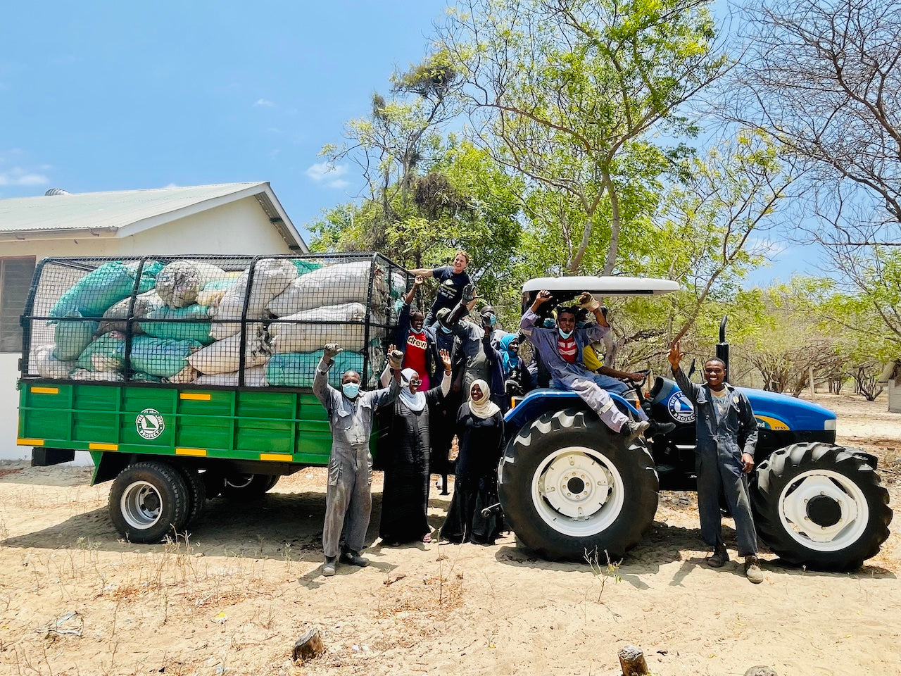 Group of people posing with a tractor and trailer in an outdoor setting