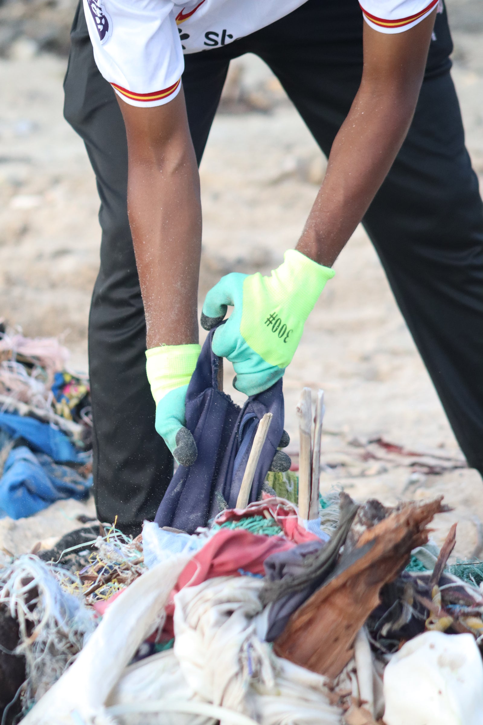 Person cleaning up trash with gloves on a beach